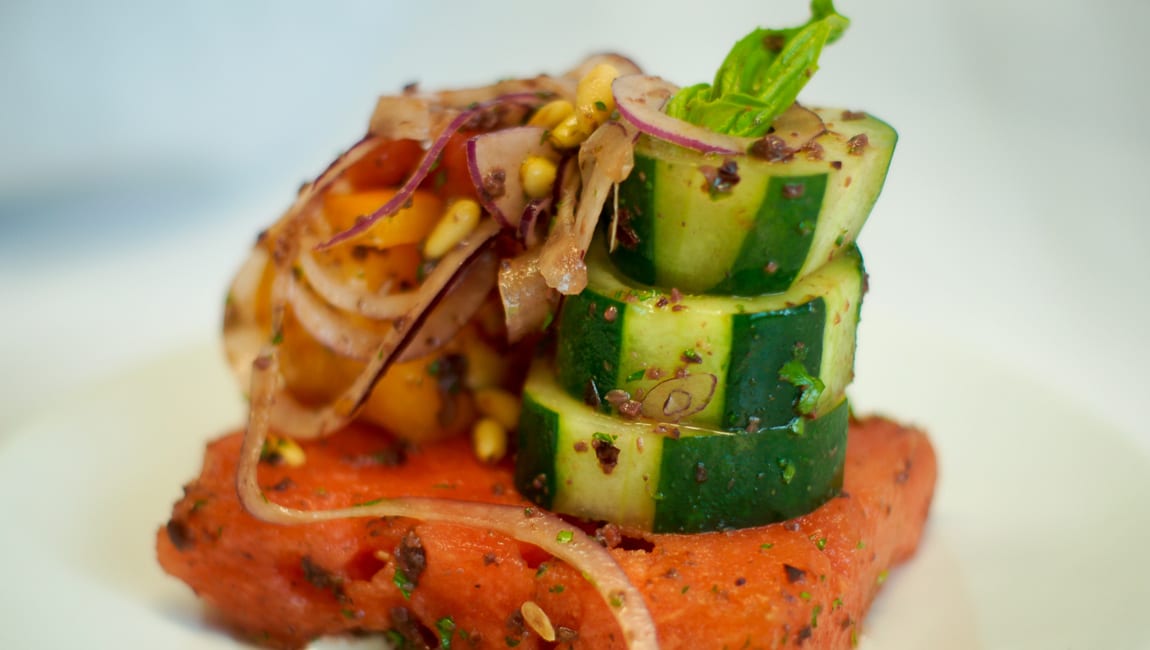 a plate of food with salmon, cucumber, and vegetables