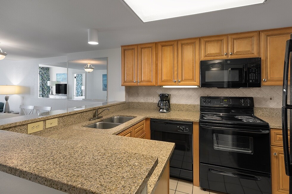 A kitchen with granite countertops, wood cabinets, and black appliances.