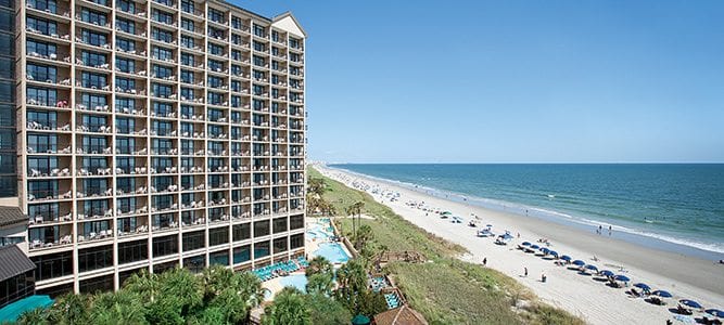 A large beachfront hotel with a pool and balconies overlooking the ocean.